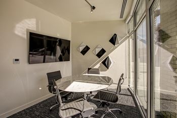 A conference room with a table and chairs and a wall-mounted monitor.